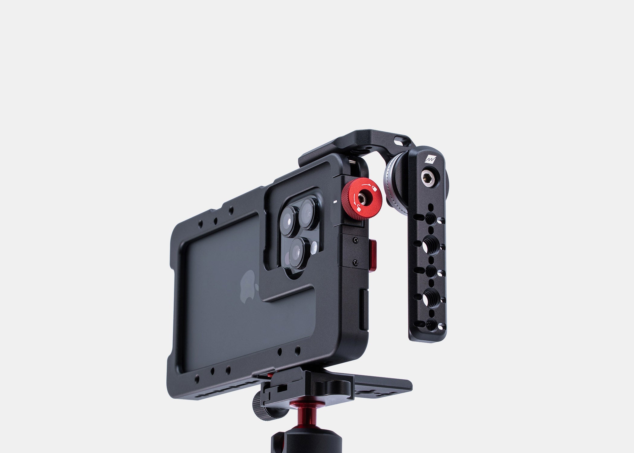 Studio shot of Beastgrip LT Mount attached to the top left side of the Beastcage for iPhone 16 Pro or 16 Pro Max, facing the back side — rig mounted on a tripod using the Beastgrip Quick Release Plate, with support for NATO rail and ARRI rosette handles.