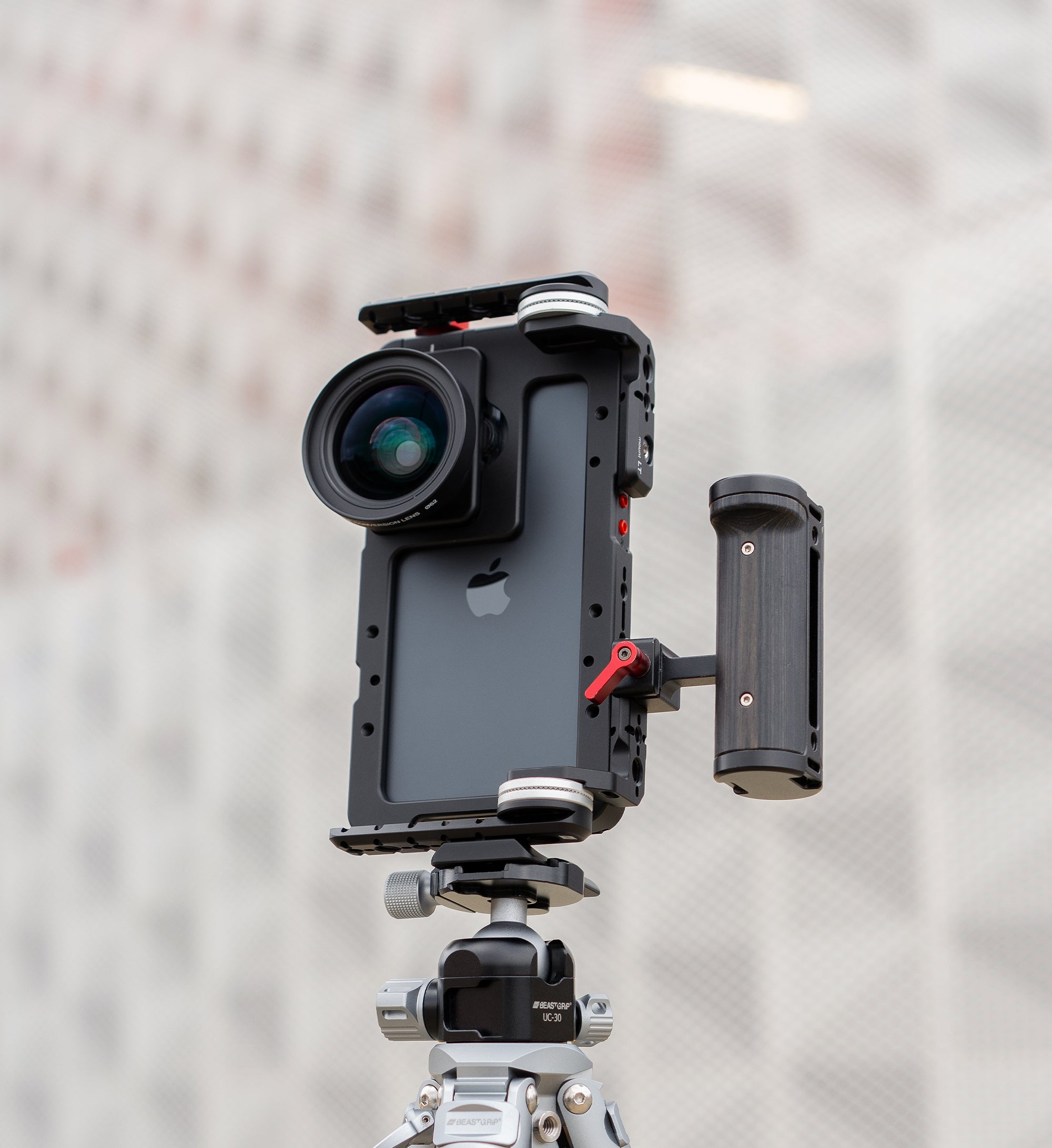 Lifestyle shot of Beastcage rig mounted vertically to tripod via Beastgrip RT Mount, with LT Mount attached to the rig and side handle mounted on RT Mount — vertical mobile video setup with 0.75X wide-angle lens and Beastcam app for iPhone filmmaking.
