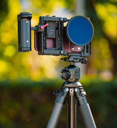 Close-up lifestyle shot of the Beastgrip BT-200 carbon fiber tripod supporting a Beastgrip Pro universal smartphone rig with iPhone 18 Pro.
