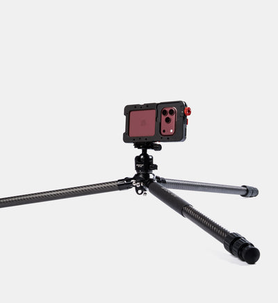 Beastgrip BT-200 carbon fiber tripod in a low-angle shooting position with legs spread wide, supporting a Beastcage rig with iPhone 18 Pro.